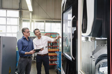 Businessmen in factory, having a meeting, using digital tablet - DIGF09763