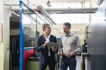 Businessmen in factory, having a meeting, using digital tablet - DIGF09802