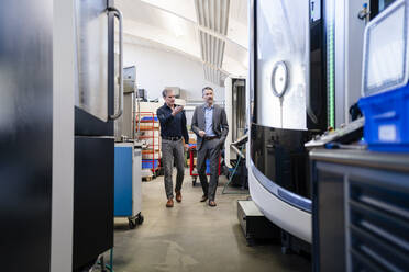 Businessmen in factory having a meeting in production hall - DIGF09832