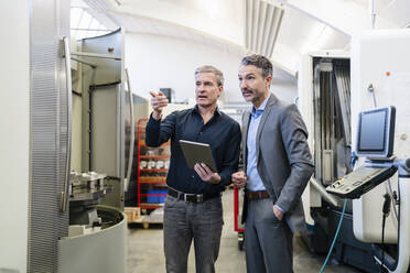 Businessmen in factory, having a meeting, using digital tablet - DIGF09837