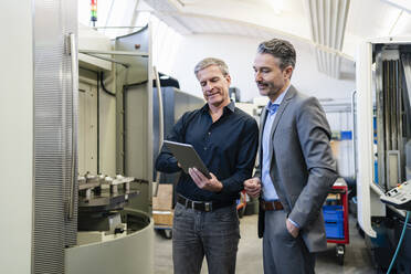 Businessmen in factory, having a meeting, using digital tablet - DIGF09839