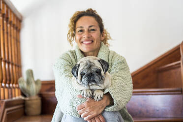 Woman sitting on stairs, with pug on her lap - SIPF02156