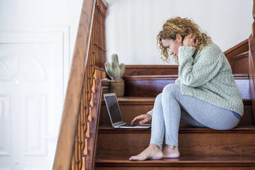 Frau sitzt auf einer Treppe und benutzt einen Laptop - SIPF02157