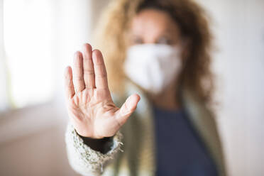 Woman with face mask showing palm of her hand, saying stop - SIPF02159