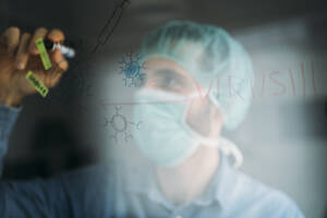 Businessman drawing coronavirus diagram on glass during quarantine period at home, Almeria, Spain, Europe - MPPF00861