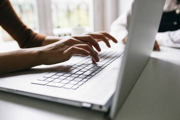 Abgeschnittenes Bild einer Geschäftsfrau, die an einem Laptop am Schreibtisch im Büro arbeitet - ABZF03086