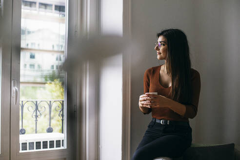 Nachdenklicher Blick durch das Fenster beim Kaffeegenuss im Büro während der Pause - ABZF03088