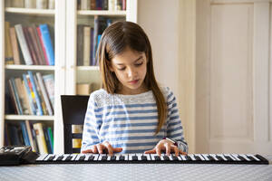 Girl playing roll piano at home - LVF08833