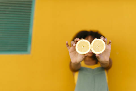 Close-up of young woman holding halved lemons stock photo