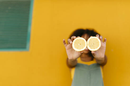 Close-up of young woman holding halved lemons - TCEF00481