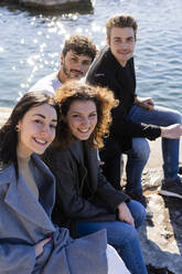 Porträt von vier Freunden, die am Gardasee sitzen, Italien - GIOF08114