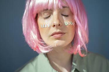 Junge Frau mit rosafarbener Perücke, Buchstaben im Gesicht, freiem Untergang, mit geschlossenen Augen - AFVF06080