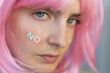 Porträt einer jungen Frau mit rosa Perücke und dem Wort 