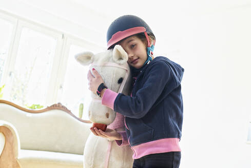 Mädchen kuschelt zu Hause mit ihrem Spielzeugpferd - DIKF00463