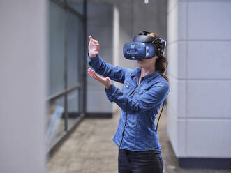 Woman wearing VR glasses and headset in modern office - CVF01592