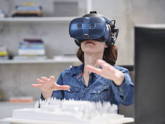 Woman wearing VR glasses and headset in modern office - CVF01595