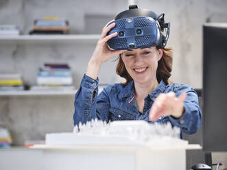 Lächelnde Frau nimmt VR-Brille im modernen Büro ab - CVF01596