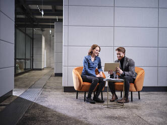 Businessman with tablet and businesswoman having a meeting in modern office - CVF01610