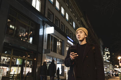 Mann benutzt Smartphone in der Stadt bei Nacht - AHSF02268