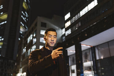 Man using smartphone in the city at night - AHSF02269