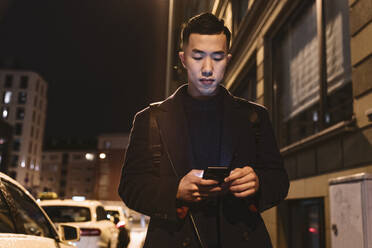 Man using smartphone in the city at night - AHSF02270