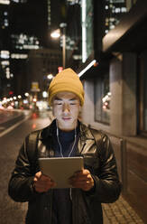 Mann benutzt Tablet in der Stadt bei Nacht - AHSF02280