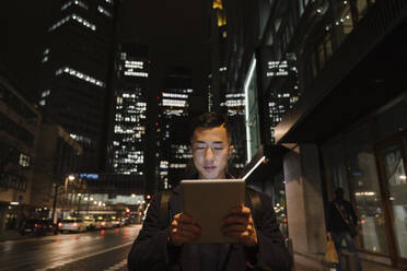 Man using tablet in the city at night - AHSF02281