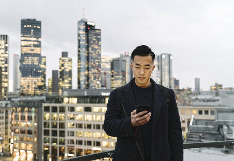 Man using smartphone in the city at dusk stock photo