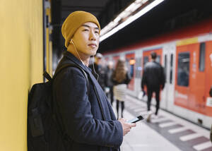 Stilvoller Mann mit gelbem Hut und Kopfhörern in der U-Bahn-Station - AHSF02289