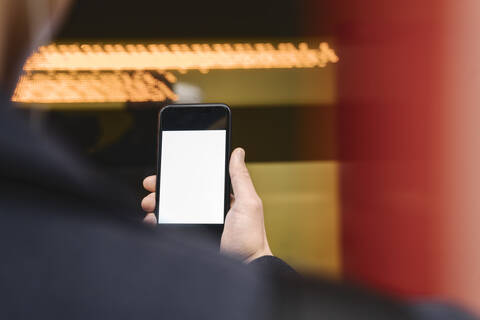 Close-up of man holding smartphone in metro station stock photo
