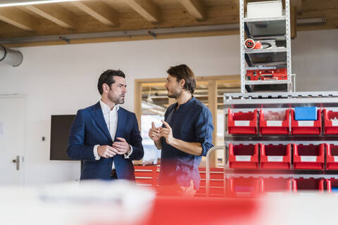 Geschäftsmann und Angestellter im Gespräch in einer Fabrik, lizenzfreies Stockfoto