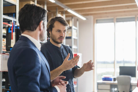 Geschäftsmann und Angestellter im Gespräch in einer Fabrik, lizenzfreies Stockfoto