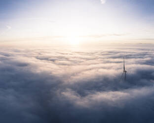 Germany, Aerial view of wind turbine shrouded in clouds at sunrise - WFF00326