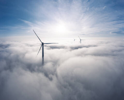 Germany, Aerial view of wind turbines shrouded in clouds at sunrise stock photo