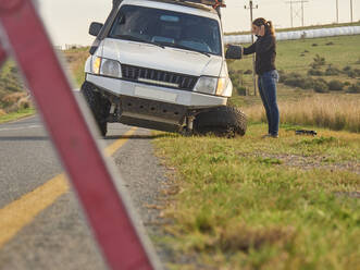 Safety triangle warning of a car accident on the side of the road with woman on the phone, South Africa - VEGF01916