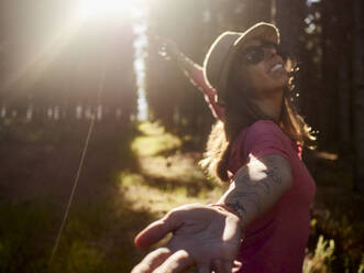 Happy woman on a forest glade in backlight, Swellendam, South Africa - VEGF01926