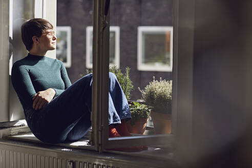 Frau sitzt am Fenster zu Hause - MCF00667