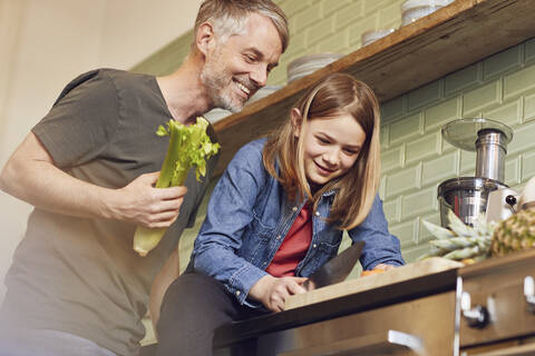 Glücklicher Vater und Tochter in der Küche bei der Zubereitung von Gemüse, lizenzfreies Stockfoto