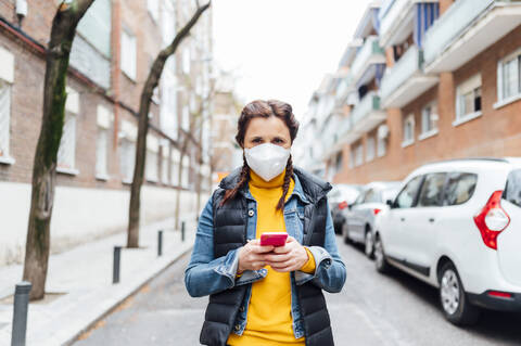 Woman wearing protective mask and using smartphone stock photo