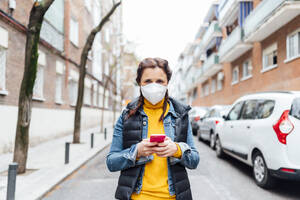Woman wearing protective mask and using smartphone - JCMF00586