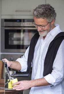 Lächelnde Reife mit Espressomaschine in der Küche - LBF03040