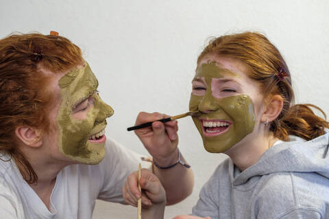 Bruder trägt Gesichtsmaske auf das Gesicht seiner Schwester auf, lizenzfreies Stockfoto