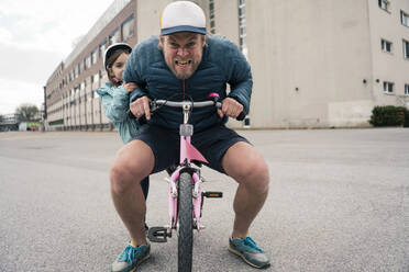 Verspielter Vater mit Tochter auf ihrem Fahrrad - JOSEF00290