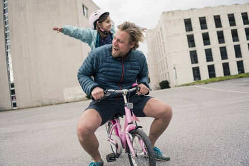 Playful father with daughter on her bicycle - JOSEF00294