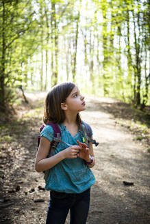 Porträt eines Mädchens mit Rucksack auf einem Waldweg - LVF08841