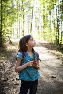 Portrait of girl with backpack standing on forest track - LVF08841