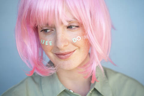 Junge Frau mit rosa Perücke, Buchstaben im Gesicht, Freiheit, lizenzfreies Stockfoto
