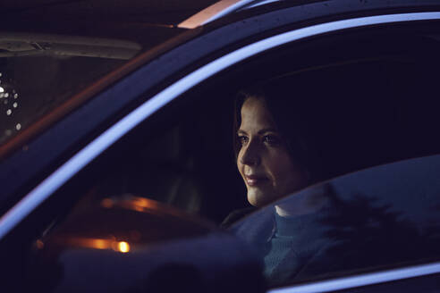 Porträt einer selbstbewussten Frau im Auto bei Nacht - MCF00730