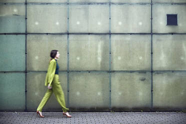 Fashionable african woman in stylish outfit walking over blue background.  Female fashion model in studio holding a jacket. stock photo