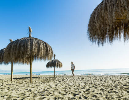 Mann, der am Strand zwischen Sonnenschirmen in Alamos Beach spazieren geht, - CAVF79072